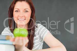 Beautilful young woman showing an apple with the camera focus on