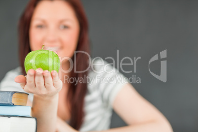 Cute student showing an apple with the camera focus on the fruit
