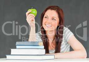 Young student in a classroom looking at an apple