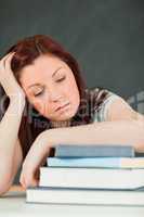Young student fallling asleep with her forearm on her books