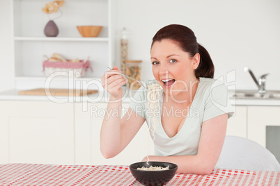 Beautiful woman posing while eating a bowl of pasta