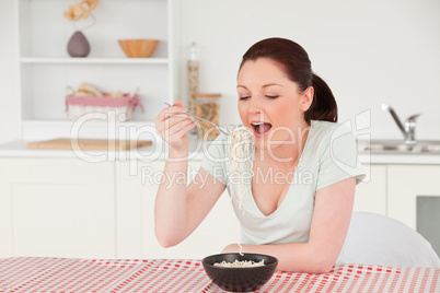 Good looking woman posing while eating a bowl of pasta