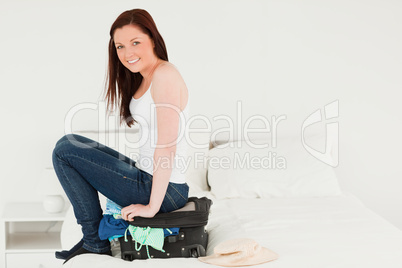 Pretty woman sitting on her suitcase