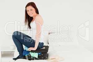 Pretty woman sitting on her suitcase