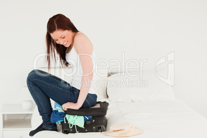 Good looking woman sitting on her suitcase