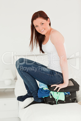 Beautiful woman sitting on her suitcase