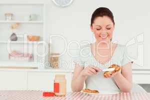 Good looking woman preparing a slice of bread and marmalade