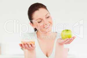 Pretty woman posing while holding a donut and a green apple