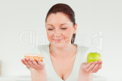 Attractive woman posing while holding a donut and a green apple