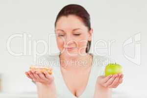 Attractive woman posing while holding a donut and a green apple