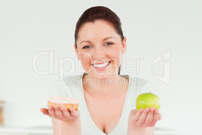Good looking woman posing while holding a donut and a green appl