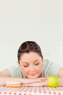 Charming woman posing with a donut and a green apple