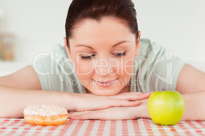 Good looking woman posing with a donut and a green apple