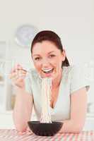 Good looking woman posing while eating pasta