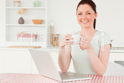 Attractive woman relaxing on her laptop while drinking a cup of