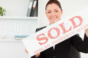 Beautiful real estate agent holding a sold placard