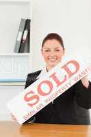 Young real estate agent holding a sold placard