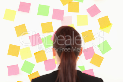 Red-haired woman looking at a wall full of repositional notes