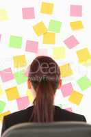 Redhead woman looking at a wall full of repositional notes