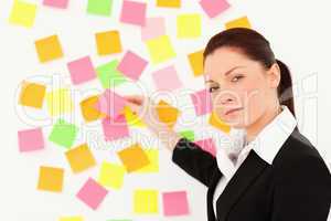 Serious woman putting repositionable notes on a white wall