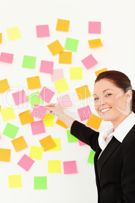 Smiling woman putting repositionable notes on a white wall