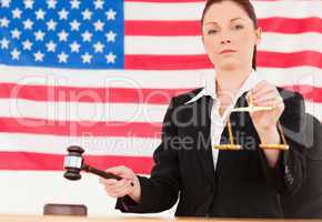 Close up of a cute judge knocking a gavel and holding scales of