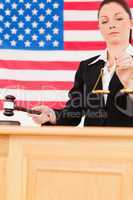 Portrait of a cute judge knocking a gavel and holding scales of