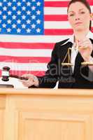 Portrait of a young judge knocking a gavel and holding scales of