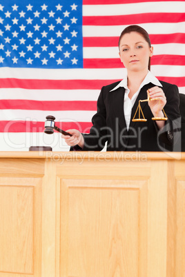 Young judge knocking a gavel and holding scales of justice