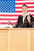 Young judge knocking a gavel and holding scales of justice