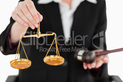 Young woman holding scales of justice and a gavel with the camer
