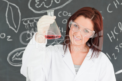 Close up of a cute scientist showing a conical flask