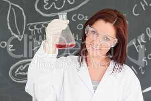 Close up of a cute scientist showing a conical flask