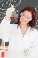 Portrait of a cute scientist looking at a conical flask