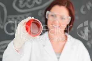 Redhead scientist holding a petri dish with the camera focused o