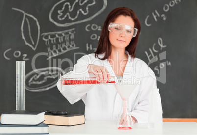 Smiling scientis pouring a liquid in a conical flask