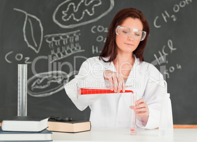 Focused young scientist pouring a liquid in a gratuated cylindre