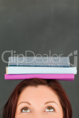 Happy young woman wearing books on her head with the camera focu