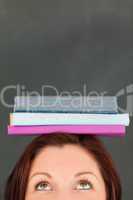 Happy young woman wearing books on her head with the camera focu