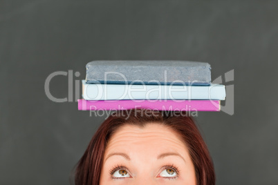 Young caucasian wearing books on her head with the camera focuse