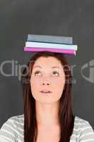 Young woman looking at the books she is wearing on her head