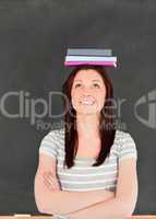 Portrait of a smilling cute woman balancing books on her head