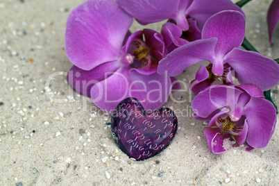 Orchideenblüte mit  Herz im Sand