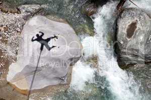 Falling bungee jumper shadow above mountain river