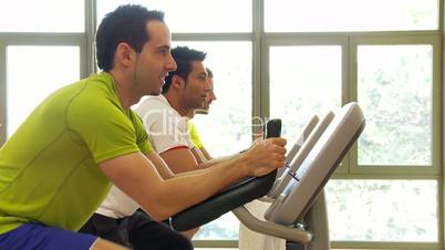 Drei Männer im Fitnessstudio auf dem Ergometer