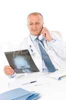 Mature doctor male with x-ray on phone