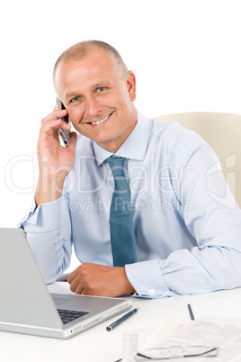 Smiling businessman sitting in office behind desk