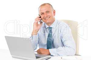 Smiling businessman sitting in office behind desk