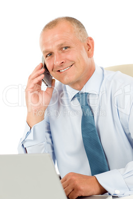 Smiling businessman sitting in office behind desk