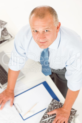 Senior man standing above office table